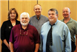 Image of five commissioners standing and smiling for camera