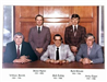 Five male commissioners sitting and standing for camera