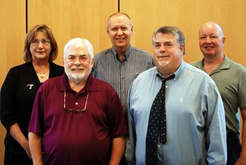 Image of five commissioners standing and smiling for camera